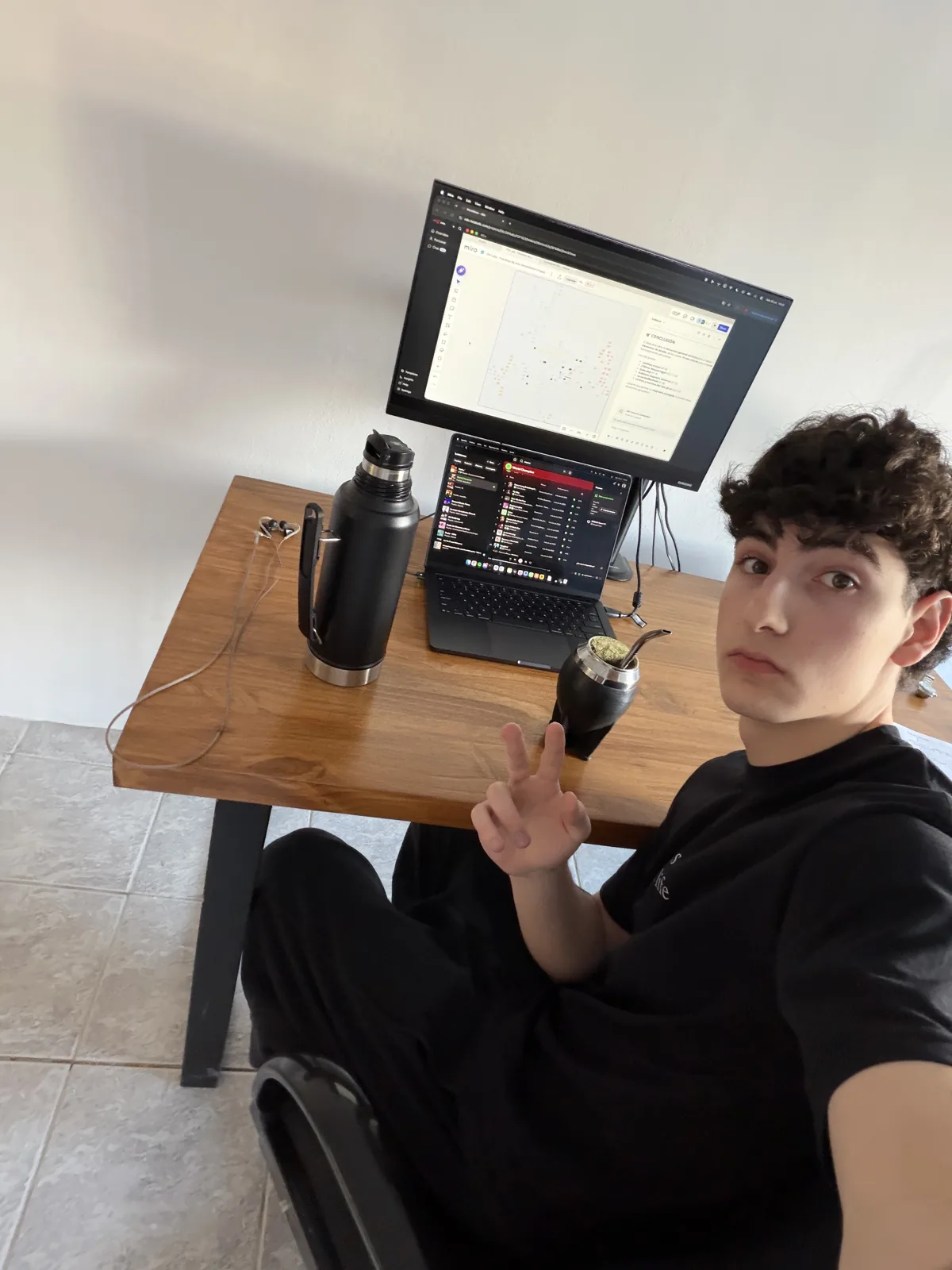 Faustino en su escritorio, con el mate y las pantallas de trabajo detrás.